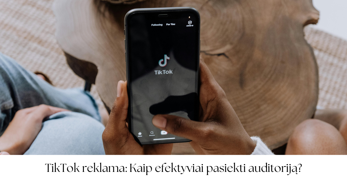 Asmuo laiko išmanųjį telefoną su atidaryta TikTok programėle ekrane